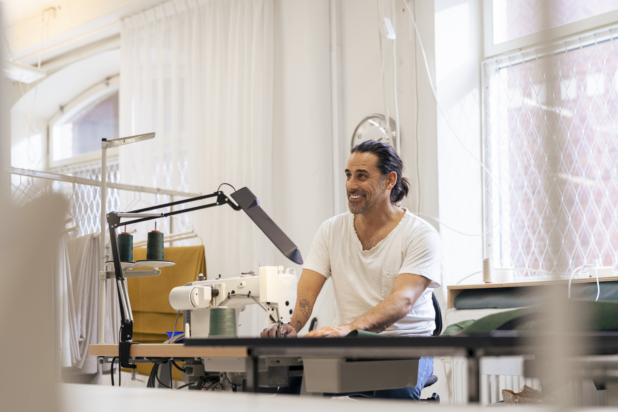 Man aan een naaitafel in een ontwerpstudio